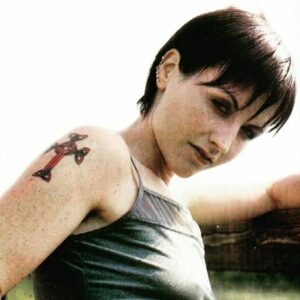 Dolores O’Riordan showing her red cross tattoo on her upper arm during a photoshoot