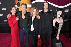 “Kevin Bacon posing with family on red carpet next to daughter showing multiple arm tattoos”