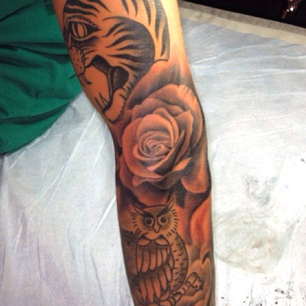 “Justin Bieber’s arm tattoo featuring a tiger, rose, and owl.”